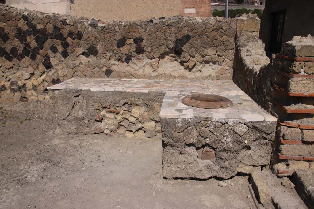 IV.10, Herculaneum, September 2021.
Looking towards west side of shop-room with two-sided counter/podium, and one dolium set in counter. Photo courtesy of Klaus Heese.
